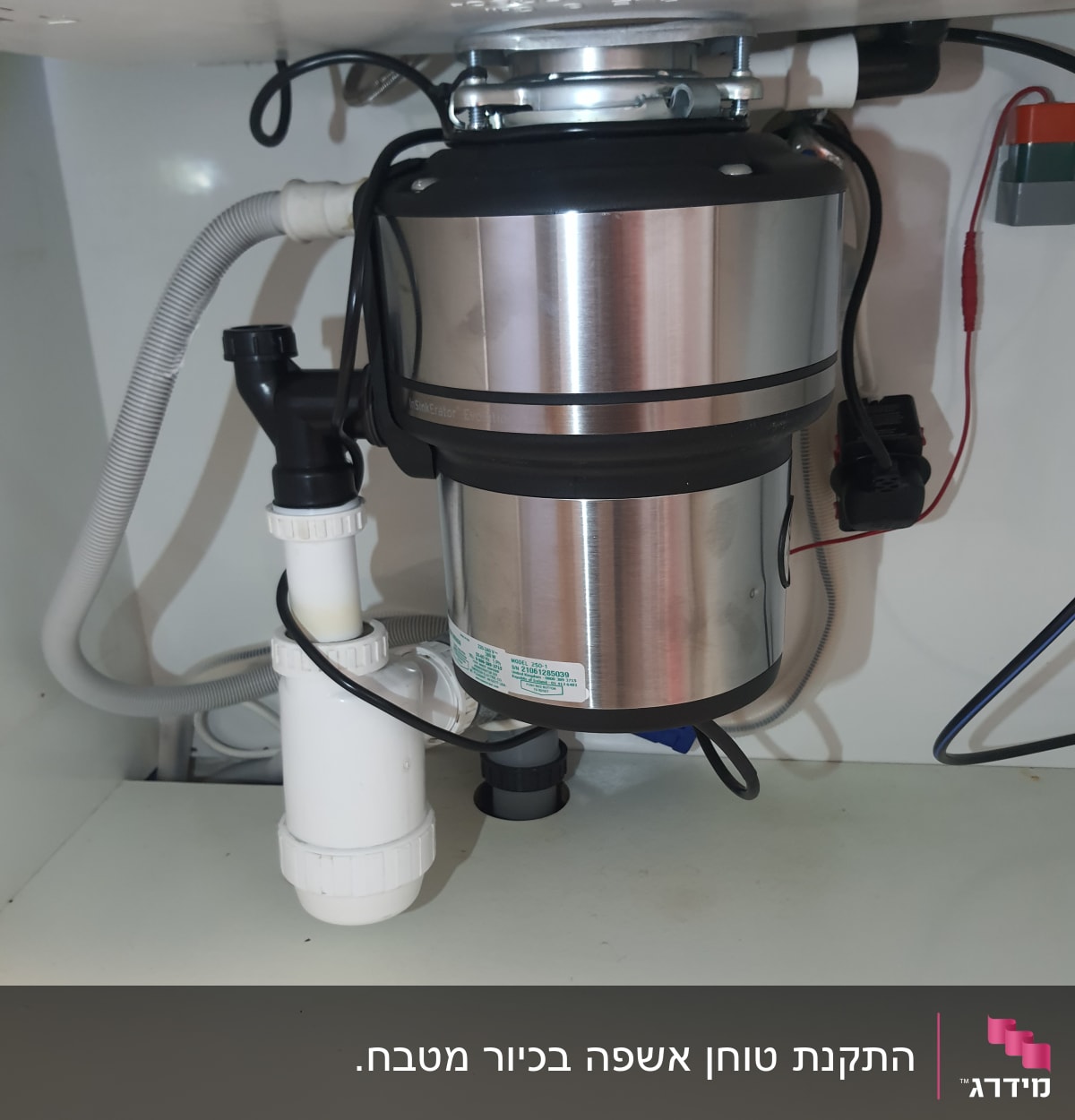 מכשיר טוחן אשפה מתחת לכיור עם צינורות חיבור